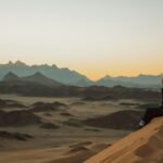 a woman sitting on top of a sand dune